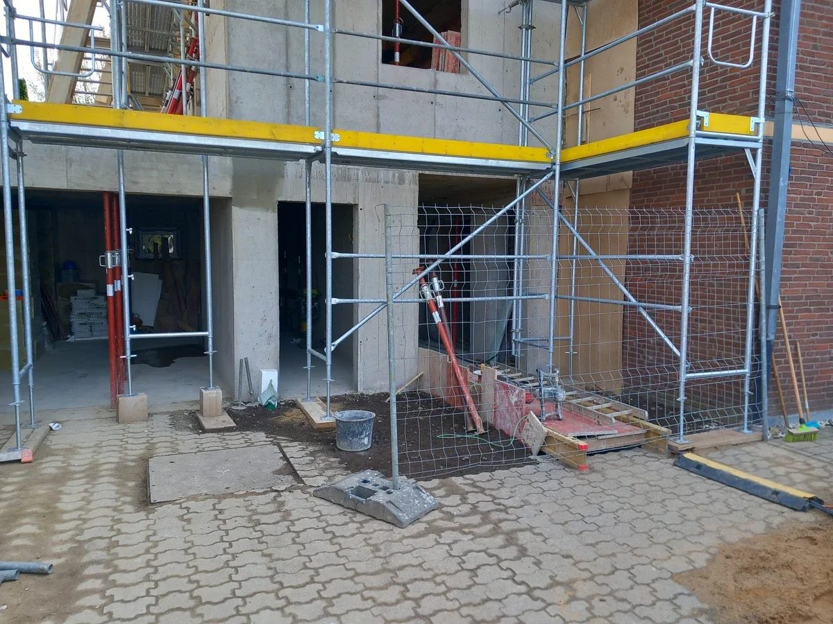 Rohbau eines Anbaus mit Gerüst und Bauaufzug