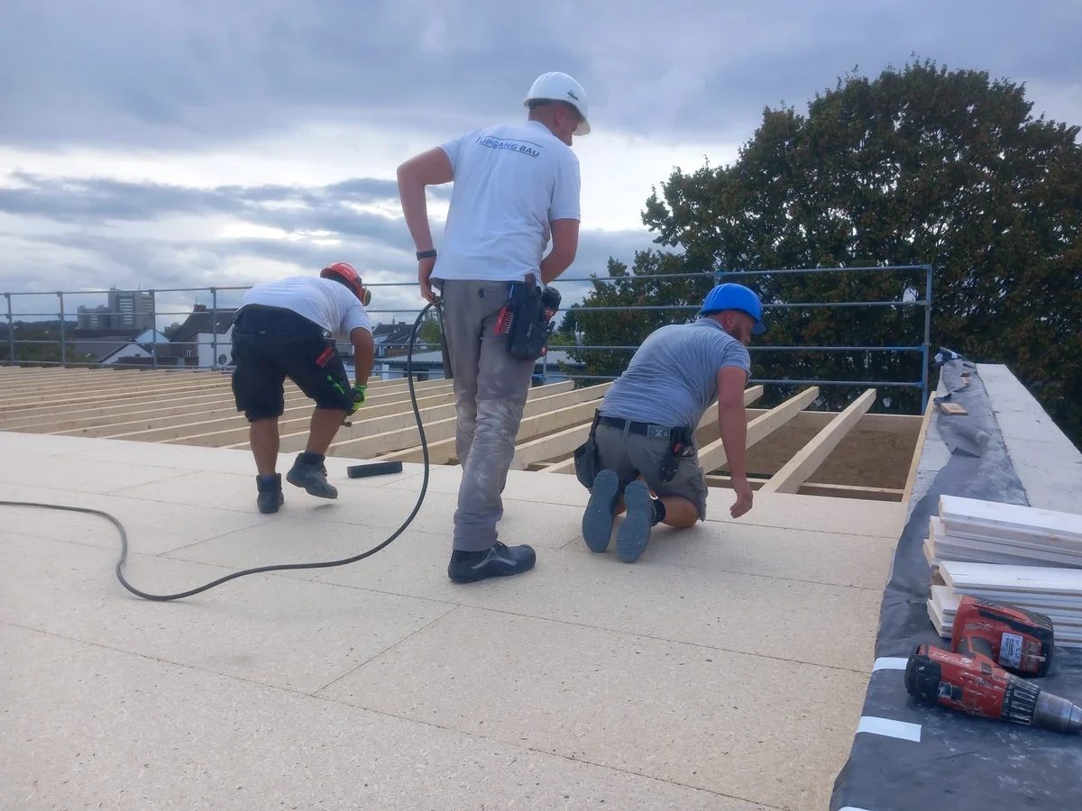 Handwerker verlegen Platten für den Dachaufbau des neuen Geschosses