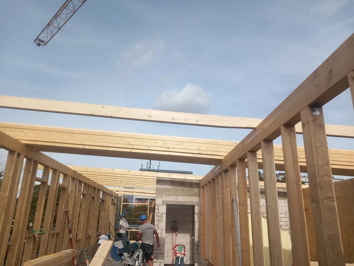 Holzrahmenwände der Aufstockung werden auf dem Bestandsgebäude errichtet